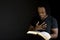 Man reading a bible isolated on black.