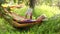 Man reading the book in cozy hammock under the trees shadows