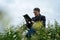 Man reading book in green hilly field. Side view of young handsome man in glasses and warm jacket reading book in open