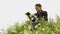 Man reading book in green hilly field. Side view of young handsome man in glasses and warm jacket reading book in open