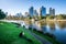 Man reading a book on Yarra riverbank promenade grass in central Melbourne and Melbourne CBD skyline in Victoria Australia