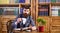 Man reading bookBusinessman sits in vintage interior, holds book and cup of tea. Bearded man in luxury suit in his