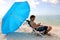 Man Reading by Ocean Under Beach Umbrella