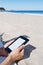 Man reading in a tablet or e-reader on the beach