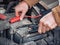 Man recharging a dead car battery in winter time using start-charger. Close up hands of a man with two contact clips