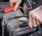 Man recharging a dead car battery in winter time using start-charger. Close up hands of a man with two contact clips