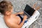 Man reclining on beach looking in laptop screen