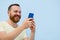 Man with a red beard looks into the phone with surprise and ecstasy a bright summer photo on a blue background