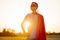 Man in a red cape of a superhero and a mask on his face, Strong confident man against the backdrop of a sunset sky