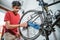 man in red clothes working fixing a trouble of the bicycle axle with a wrench