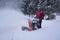 Man in Red Coat using Snow Thrower in Driveway