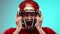 Man in red football helmet, American football player emotionally expressing intense emotion, shouting against blue