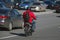 A man with a red jacket and a black backpack riding a moped