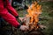 Man in the red jacket placing a firewood to the campfire