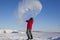 A man in a red jacket throws a bottle of boiling water into the air. Rapid freezing occurs at temperature