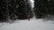 A man in a red jacket walks through a winter forest with a phone and tries to find a place in the forest where there is