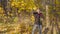 Man with red roses waiting for his beloved woman on a date in the autumn forest