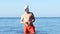 Man in red shorts with unicorn head mask dancing in the sea, strange funny weird video.