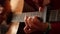 A man in a red sweater plays an acoustic guitar indoors a close-up view of an wide open aperture