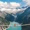 Man in a red tshirtjacket sitting on a suspension bridge above the Alps. Freedom and adventure concept. Touristic activities in