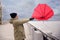 Man with red umbrella caught in gust of wind near river