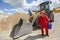 Man in red uniform with petrol can, bulldozer in background