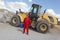 Man in red uniform with petrol can, bulldozer in background