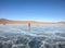 Man in red winter coat walk on frozen Baikal lake in winter