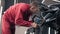 Man in red work suit polishing black car at autocenter.