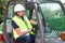 Man in reflective clothing operating heavy equipment in construction