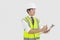 Man in reflector vest and hard hat writing on clipboard in office