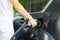 A man refueling a black car with diesel fuel at a gas station. Refueling nozzle close up and jet of fuel.