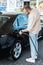 Man refueling black car while standing at gas station