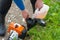 A man refuels a lawn mowers gasoline engine from a plastic tank