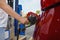 Man refuses his red car with gasoline at a gas station. Hand and black refueling gun close up