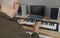 Man is rehearsing while playing on compact modern synthesizer in his home music studio.