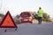 Man with relaxed attitude stranded on the road next to the broken down car talking on the phone