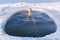 A man relaxes while swimming in a cold hole in ice water in winter