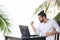 Man relaxing on the beach with laptop, freelancer show win