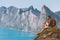 Man relaxing on cliff travel with backpack in Norway hiker enjoying mountains and fjord view