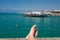 Man relaxing on the dock with crossed legs and the turquoise mediterranean sea as a background