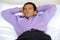 Man relaxing in hotel room with hands behind head, eyes closed