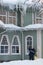 Man remove icicles from the roof with a long stick. Worker clean roof of building from dangerous icicles