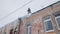 Man removing snow and icicles on the roof