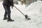 Man removing snow from sidewalk after heavy snowfall. Snowstorm and blizzard aftermath in winter. Slippery walkaway