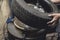 A man removing a tire from the rim after using a tire bead breaker at a vulcanizing shop