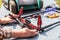 A man is repairing a battery-powered lawnmower. The electric toggle switch to start the engine is defective and needs to be