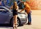 Man repairing a car for slim blonde girl