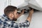 Man repairing modern cooker hood in kitchen