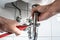 Man repairing sink trap with adjustable pipe wrench